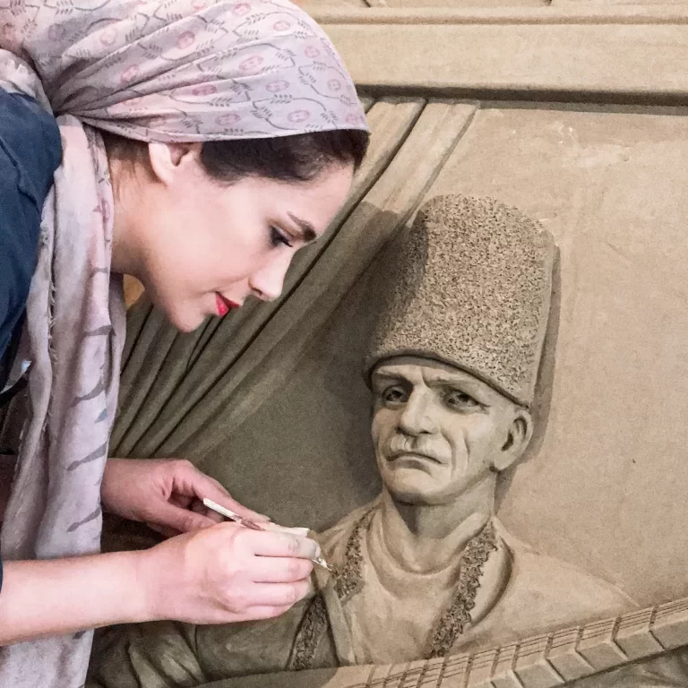 A woman artist meticulously paints a sculpture of a man, capturing the essence of his form and expression.